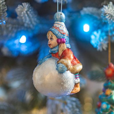 Елочная игрушка девочка лепит снеговика