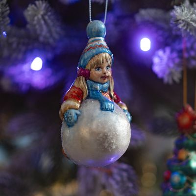 Елочная игрушка девочка лепит снеговика